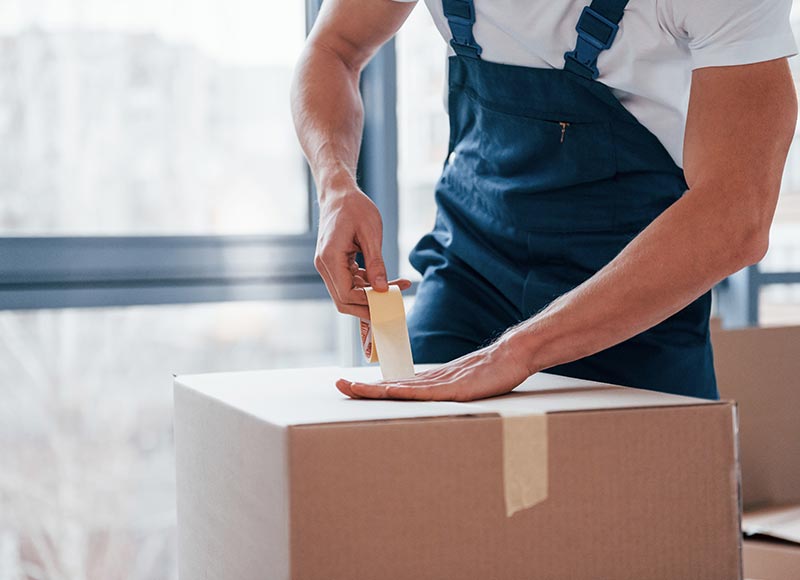 Movers and packers taping moving boxes securely to ensure safety during transit.